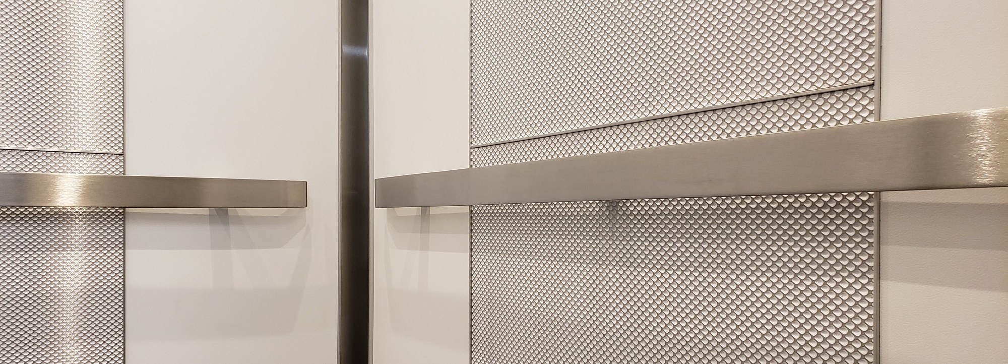 Brushed stainless flat bar handrails on textured metal and laminate panels